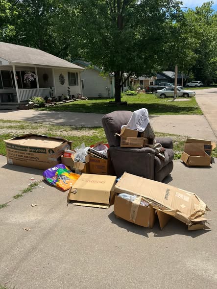 Recliner, boxes, and furniture piled at the curb before pickup