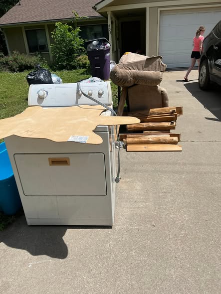 Dryer, headboard, and bagged items staged in the driveway before pickup